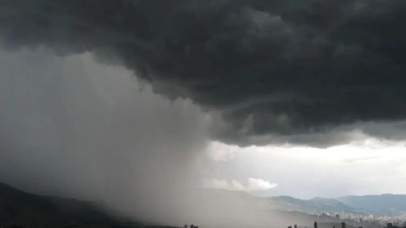 La imagen describe una panorámica de Medellín, cubierto de nubes grises instantes antes de un fuerte aguacero