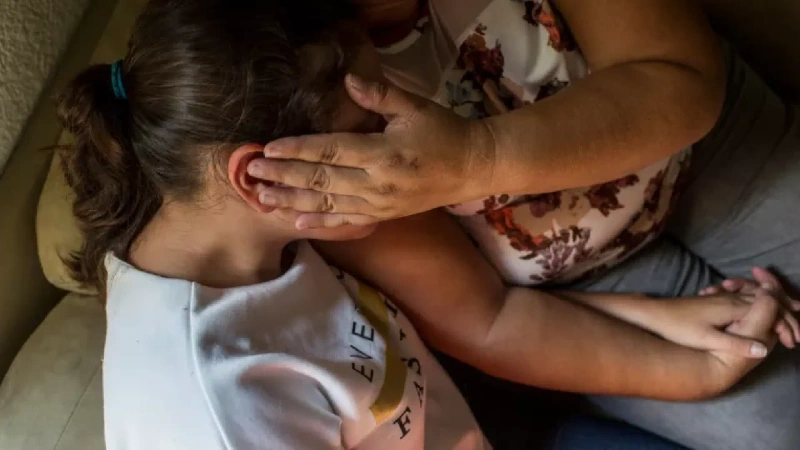 La imagen muestra como referencia a una menor siendo cuidada y protegida por una familiar adulta.