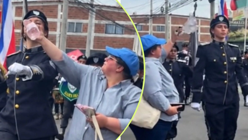 Una mamá hidrata y refresca a su hija durante el desfile de independencia en El Salvador.